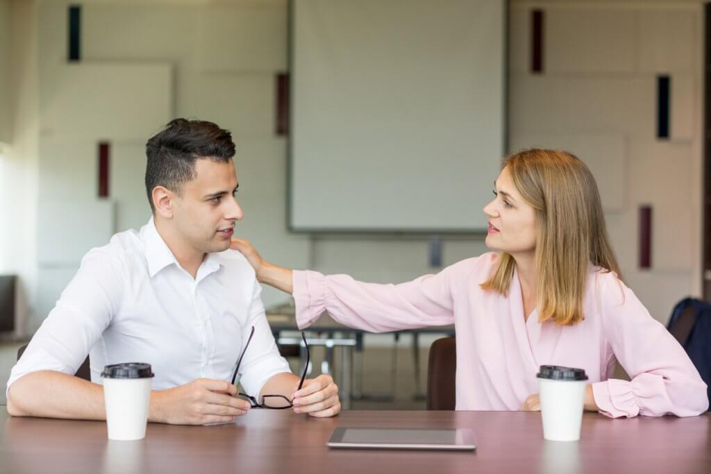 Confident businesswoman tapping male colleague on shoulder at coffee break